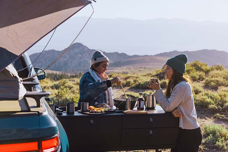 Two people cooking breakfast with the Rivian camper kitchen